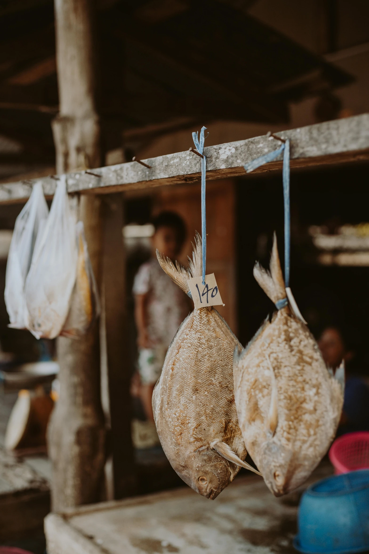 a couple of fish hanging from a wooden pole, pexels contest winner, mingei, meats on the ground, madagascar, market setting, laura watson