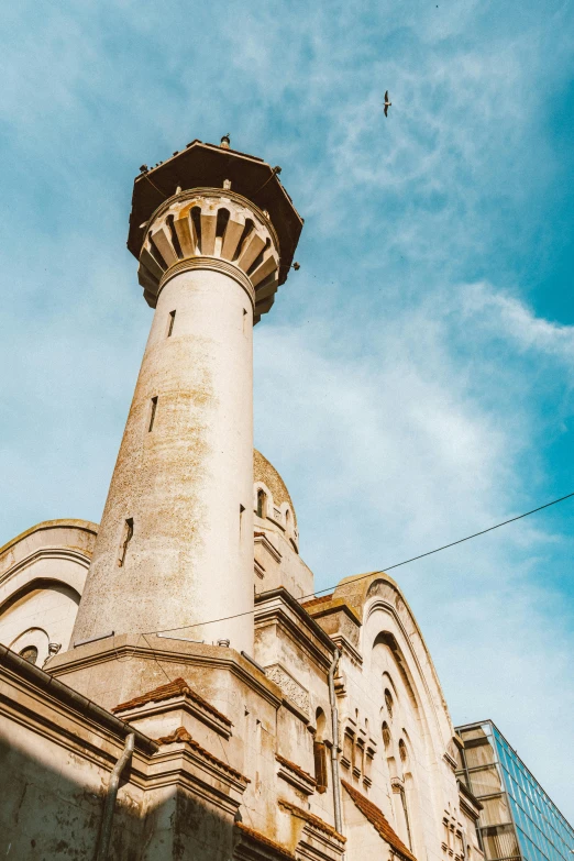 a tall building with a clock on top of it, romanesque, mosque, blue sky above, romanian heritage, pillar