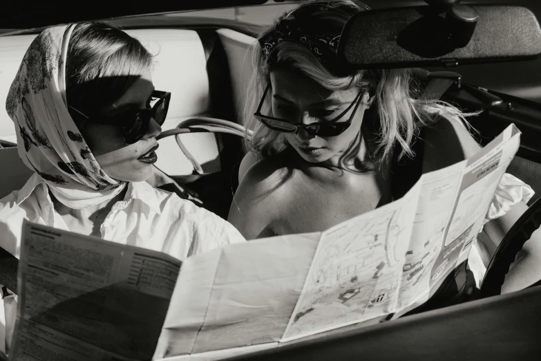 a black and white photo of two women in a car, tumblr, visual art, reading a newspaper, pamela anderson, blindfold, with a kid