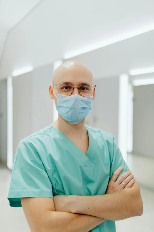 a man wearing a surgical mask in a hospital hallway, by Adam Marczyński, portrait of bald, dr 8 k, wearing round glasses, scrubs