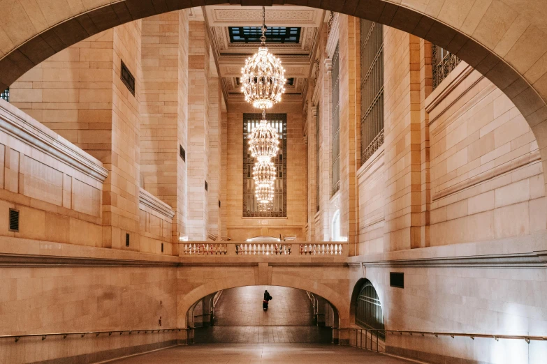 a long hallway with a chandelier hanging from the ceiling, by Alison Geissler, unsplash contest winner, new york buildings, sweeping arches, gif, set inside of the bank