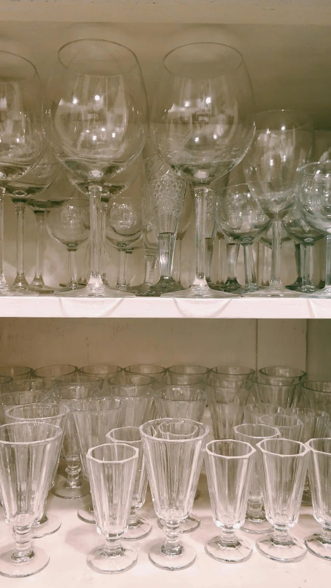 a shelf filled with lots of wine glasses, inspired by Cerith Wyn Evans, unsplash, photorealism, 1990's photo, super detail of each object, ( ( photograph ) ), taken in the late 1980s