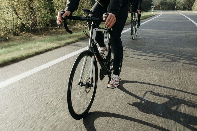 a man riding a bike down the middle of a road, profile image, legs visible, neoprene, background image