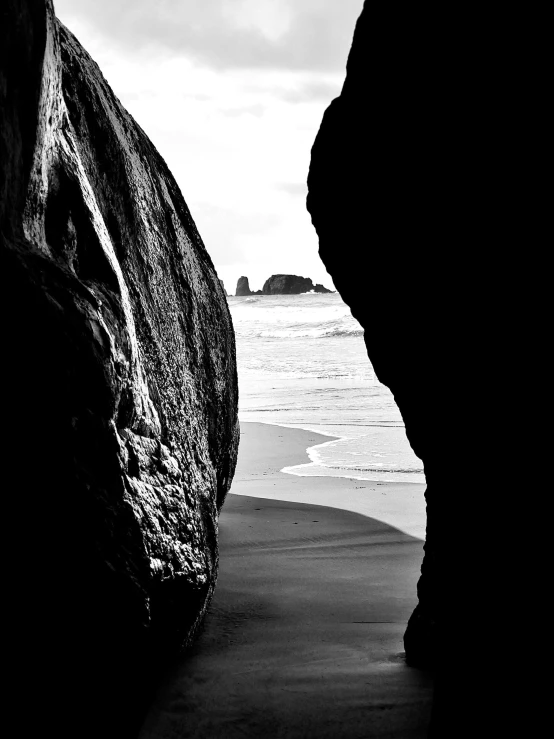 a couple of large rocks sitting on top of a beach, by Alexander Robertson, world seen only through a portal, detailed veiny muscles, monochrome:-2, jonathan ivy