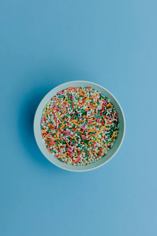 a bowl of sprinkles on a blue surface, by Nicolette Macnamara, pexels, on a gray background, colorful]”, multiple stories, 6