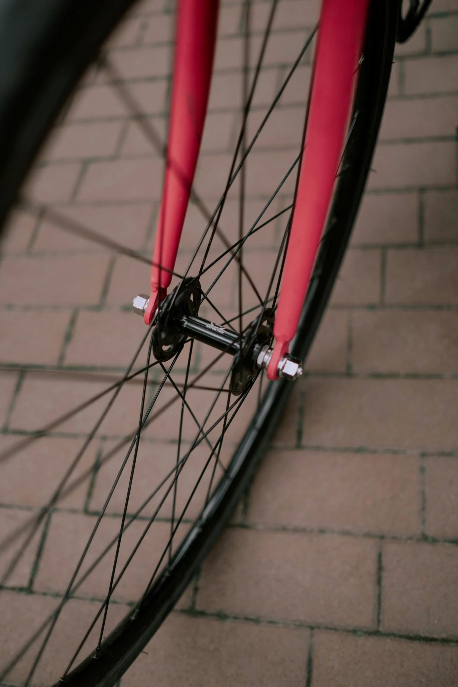 a red bike parked next to a brick wall, a picture, unsplash, purism, black wheel rims, pink and black, soft vinyl, close-up shot from behind