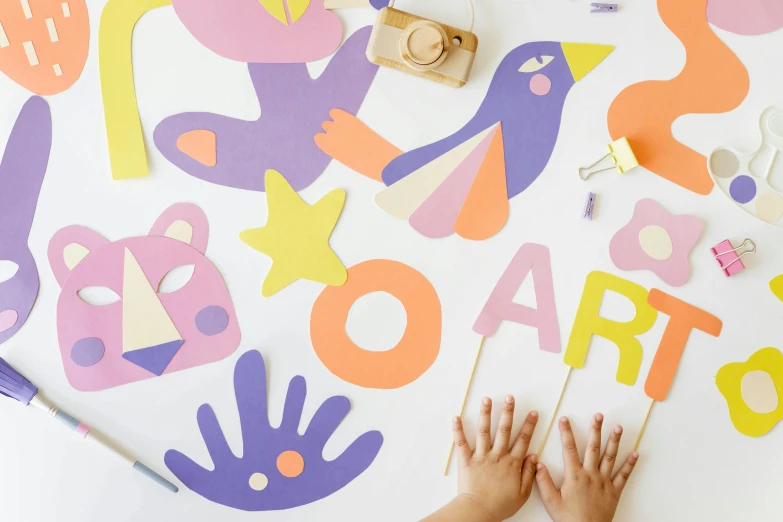 a close up of a person's hands on a table, a child's drawing, trending on pexels, interactive art, die cut sticker, orange and purple color scheme, cardboard cutout, bright signage