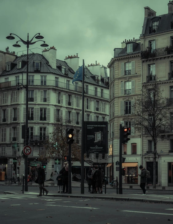 a group of people walking down a street next to tall buildings, pexels contest winner, paris school, gloomy lighting!!!, square, french village exterior, standing on street corner