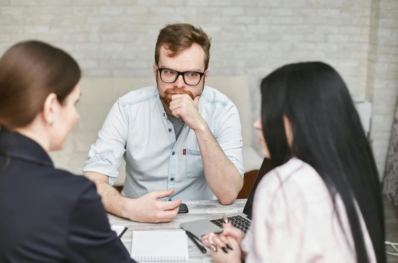 a group of people sitting around a table, man with glasses, pondering, lachlan bailey, professional image