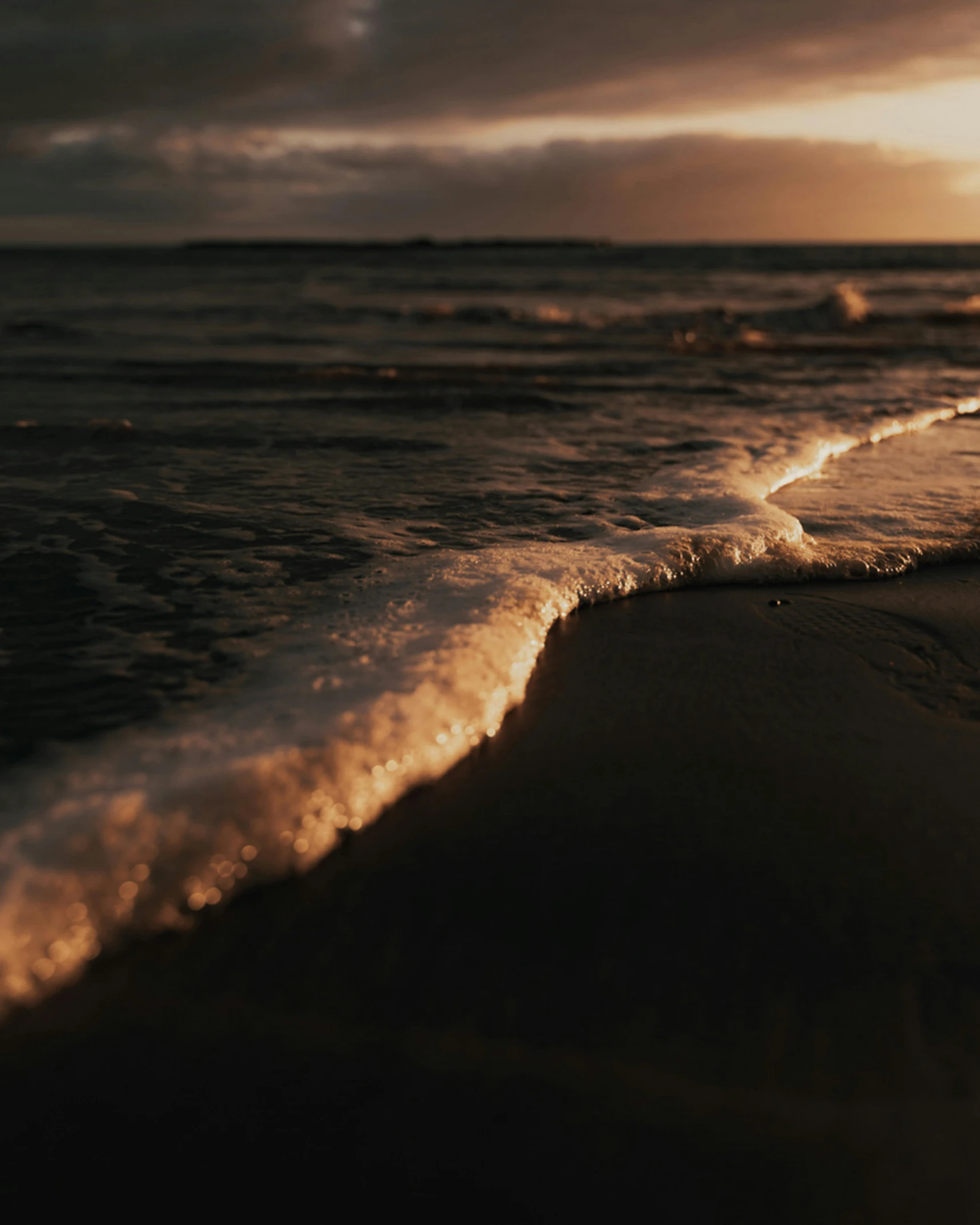 the sun is setting over the water on the beach, by Jan Tengnagel, unsplash contest winner, romanticism, foamy waves, low detailed, ignant, brown water