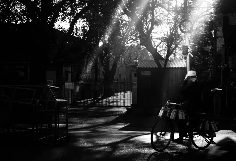 a black and white photo of a person on a bike, a black and white photo, by Sudip Roy, pexels contest winner, sunny morning light, taken in zoo, flashing lights, golden hour in beijing