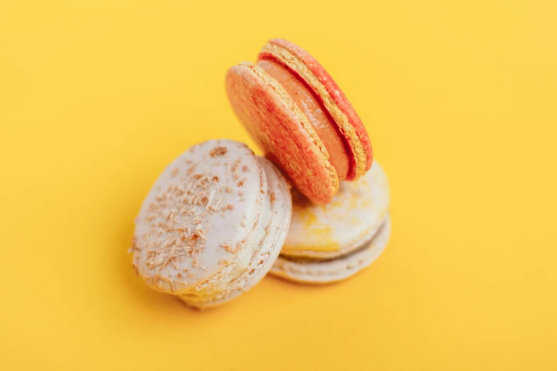 two macarons sitting next to each other on a yellow surface, a macro photograph, pexels, rococo, orange and white, detailed product image, crackles, full product shot