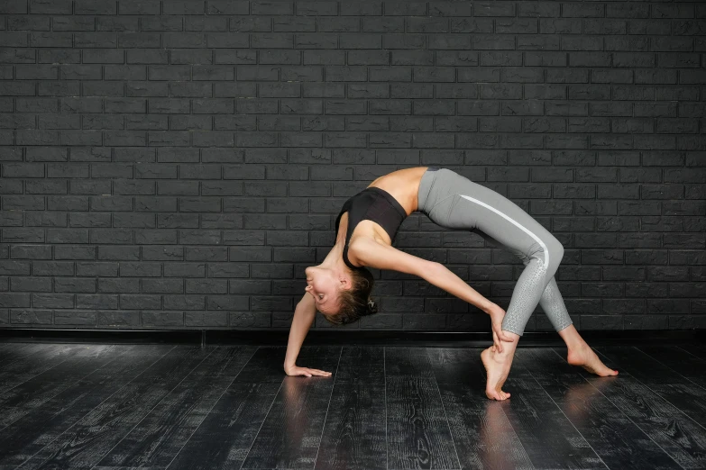 a woman doing a yoga pose in front of a brick wall, trending on pexels, arabesque, quadruped, studio photo, background image, bending down slightly