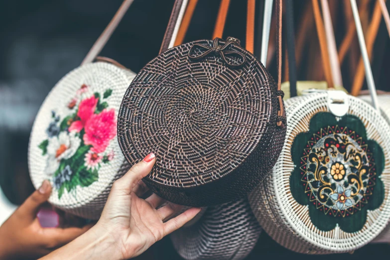 a close up of a person holding a purse, by Julia Pishtar, trending on pexels, arts and crafts movement, round shapes, bali, shops, with a bunch of stuff