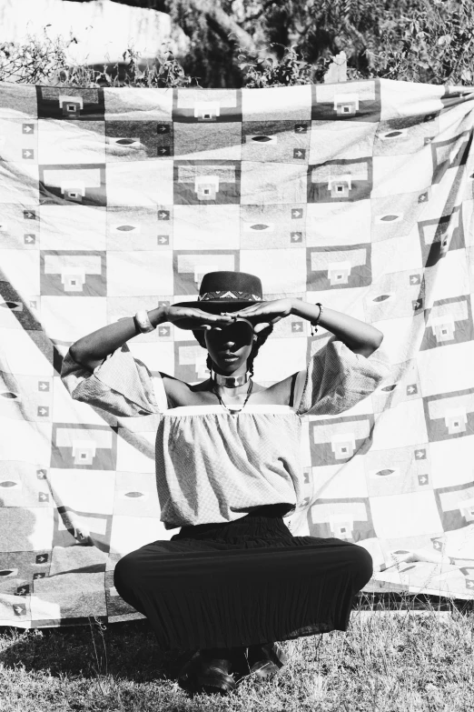 a black and white photo of a man holding a quilt, by Maurycy Gottlieb, afrofuturism, woman with hat, pose(arms up + happy), 1 9 9 2, in a square