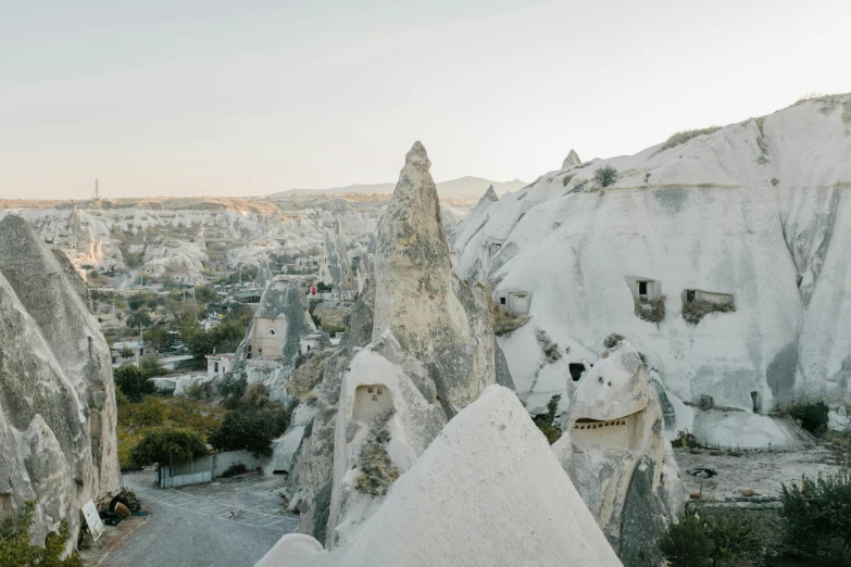 a group of people standing on top of a mountain, unsplash contest winner, surrealism, white houses, turkey, highly detailed rock structures, beige