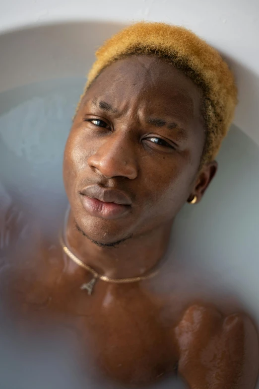 a close up of a person in a bath tub, an album cover, inspired by Candido Bido, trending on pexels, les nabis, blonde man, young thug, serene expression, black goo