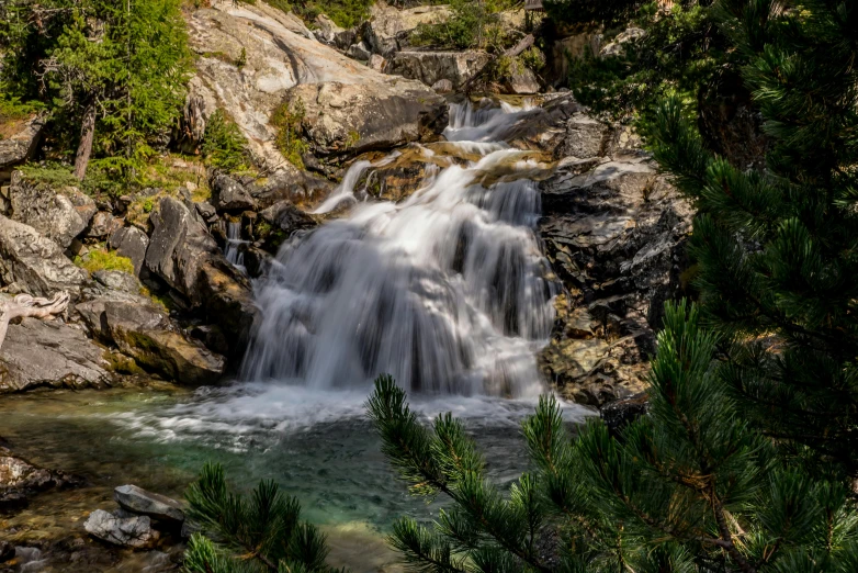 a small waterfall in the middle of a forest, by Arnie Swekel, hiking in rocky mountain, album, 8k octan photo