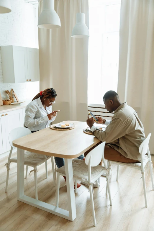 a couple of people that are sitting at a table, pexels contest winner, white kitchen table, thumbnail, low quality photo, brown