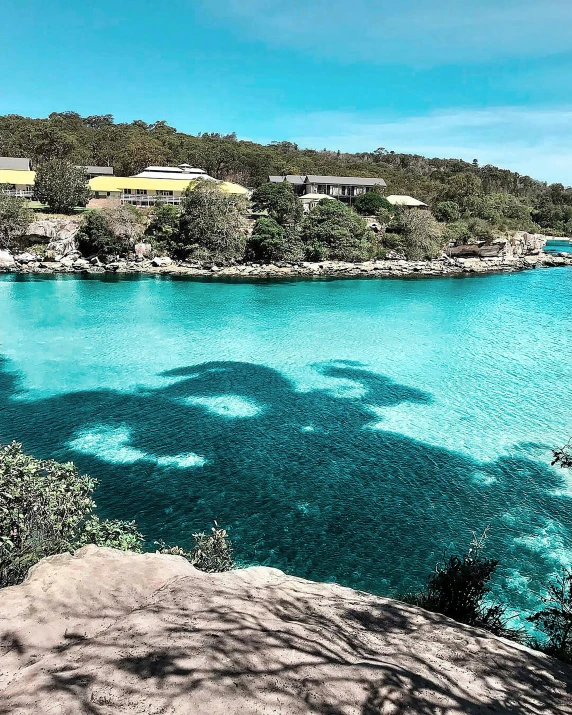 a large body of water surrounded by trees, turquoise ocean, rock pools, overlay, resort