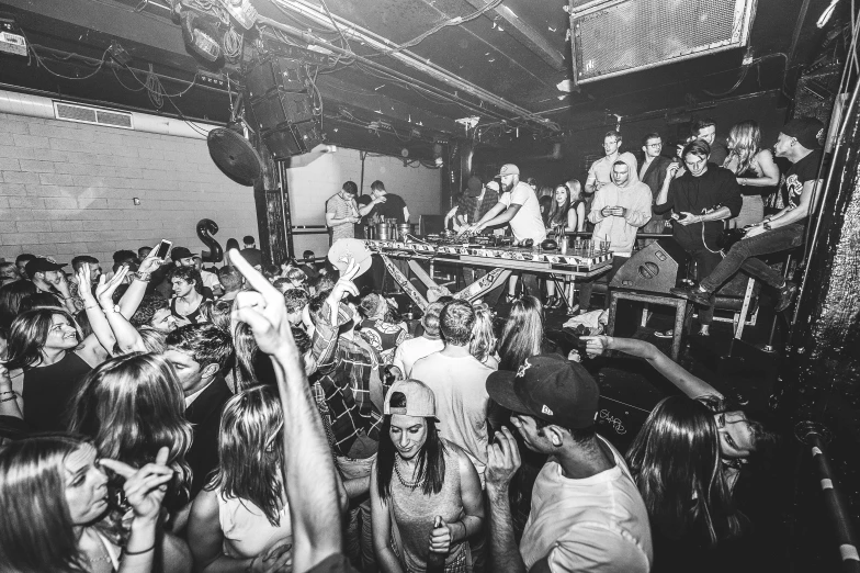 a black and white photo of a crowd of people, by Zack Stella, djing with dj turntables, adam varga, the back rooms, action bronson