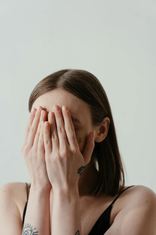 a woman covering her face with her hands, pexels contest winner, hyperrealism, facial muscles, plain background, low quality photo, blind