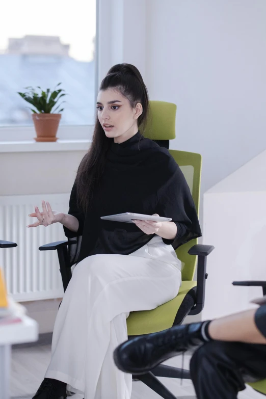 a woman sitting in a chair talking to another woman, inspired by Marina Abramović, unsplash, female in office dress, mahira khan as a d&d wizard, photograph of a techwear woman, office furniture