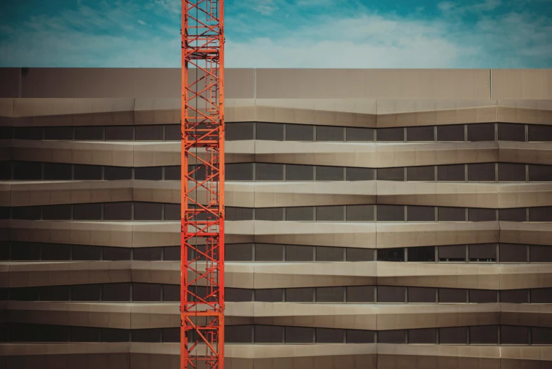 a red crane standing in front of a tall building, a photo, inspired by Robert Bechtle, pexels contest winner, constructivism, orange line, vintage color, large format, high - angle