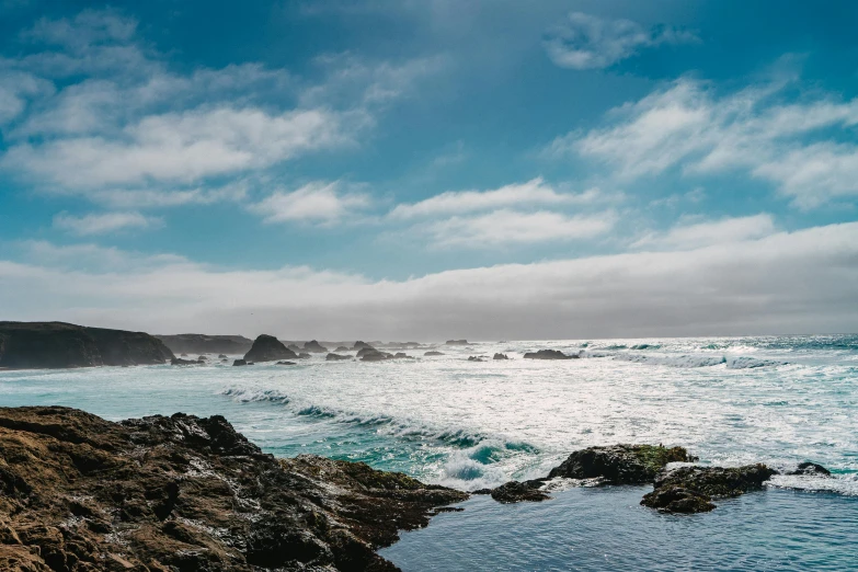 a body of water sitting on top of a rocky beach, pexels contest winner, azure waves of water, central california, swirling clouds, youtube thumbnail