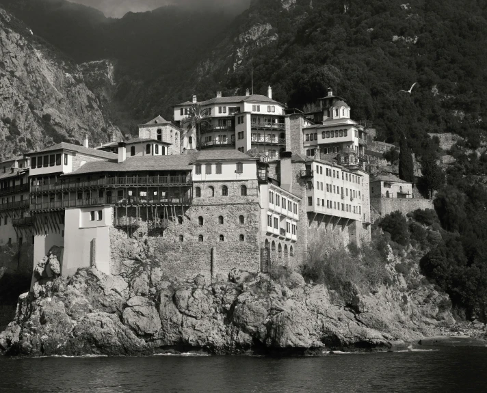 a black and white photo of a building on a cliff, a black and white photo, renaissance, boka, byzantine, brown, saint