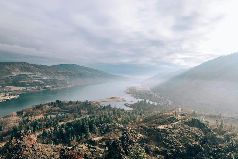 a large body of water sitting on top of a lush green hillside, by Jessie Algie, pexels contest winner, gorge in the mountain, faded and dusty, 4 k cinematic panoramic view, a quaint