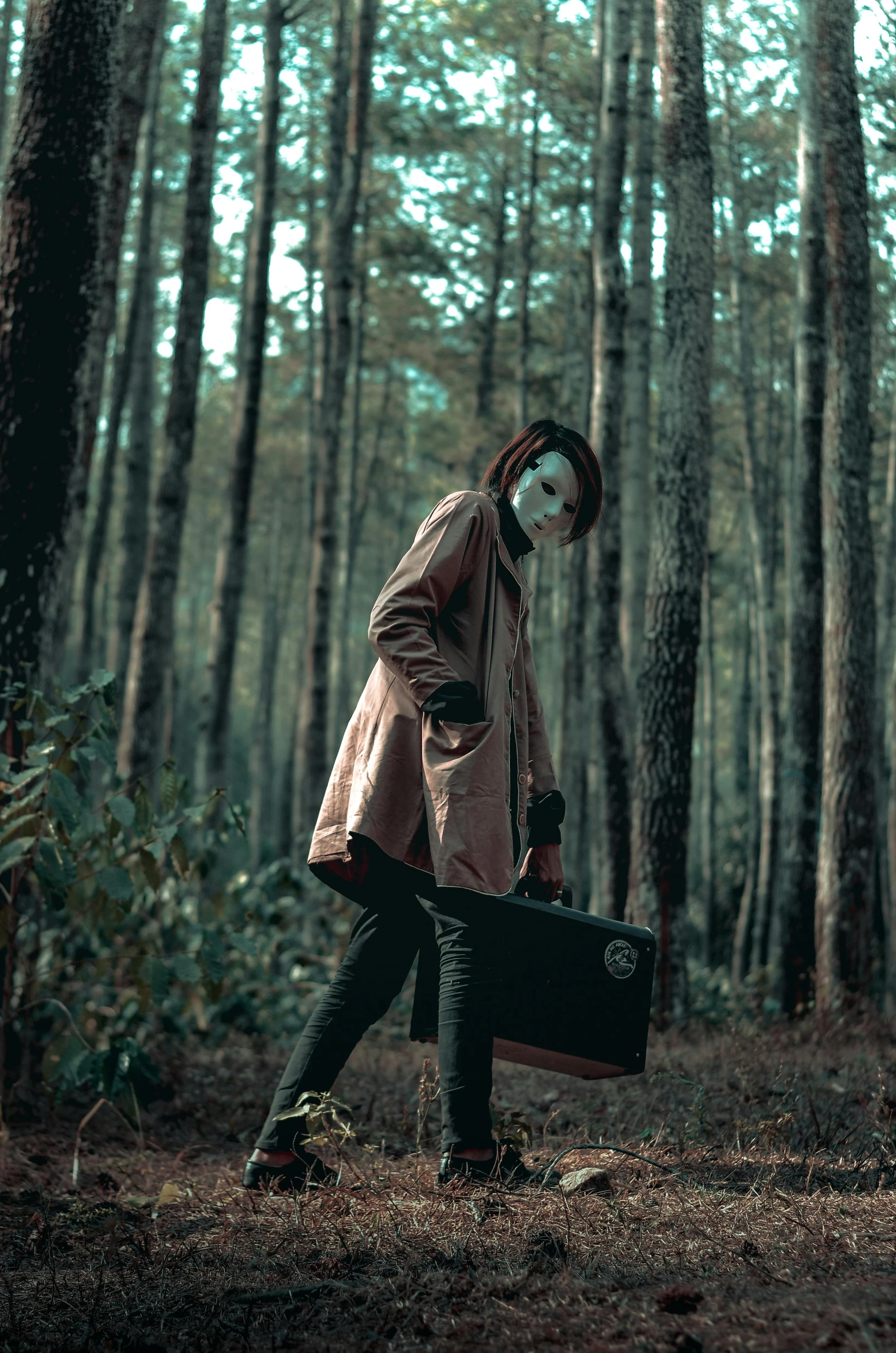 a person walking through a forest with a suitcase, an album cover, pexels contest winner, conceptual art, with black metal face paint, clown, wearing a worn out brown suit, cosplay photo