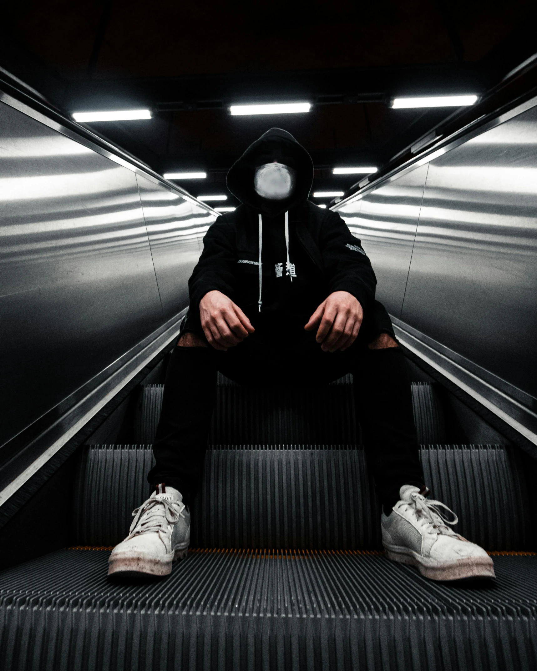 a man in a hoodie sitting on an escalator, pexels contest winner, white mask, symmetrical face and body, non-binary, sneaker photo