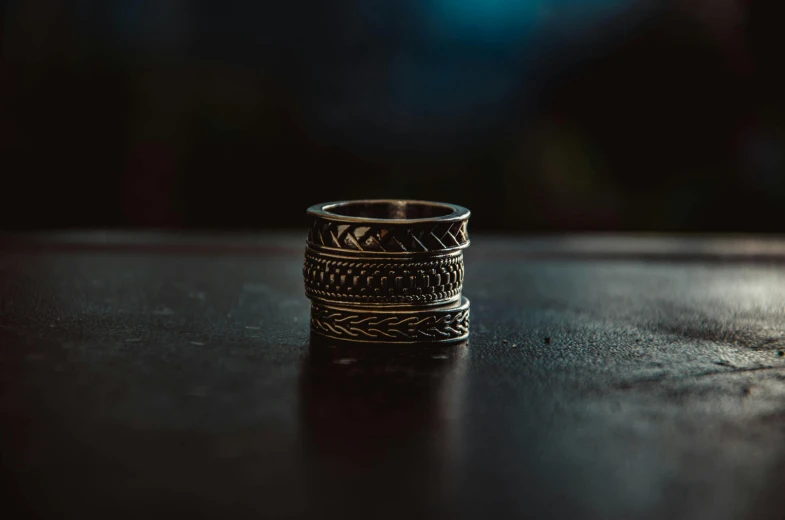 a close up of a ring on a table, an etching, trending on pexels, hurufiyya, stacked, tribal style, hyper realistic style, dimly - lit