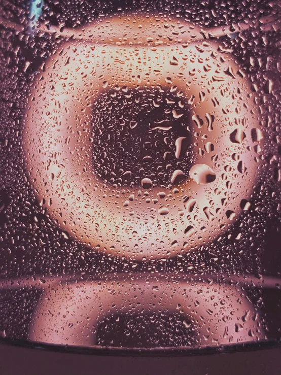 a glass filled with water sitting on top of a table, an album cover, inspired by Anish Kapoor, trending on unsplash, hyperrealism, donut, 1 9 7 0 s car window closeup, low quality grainy, made of liquid purple metal