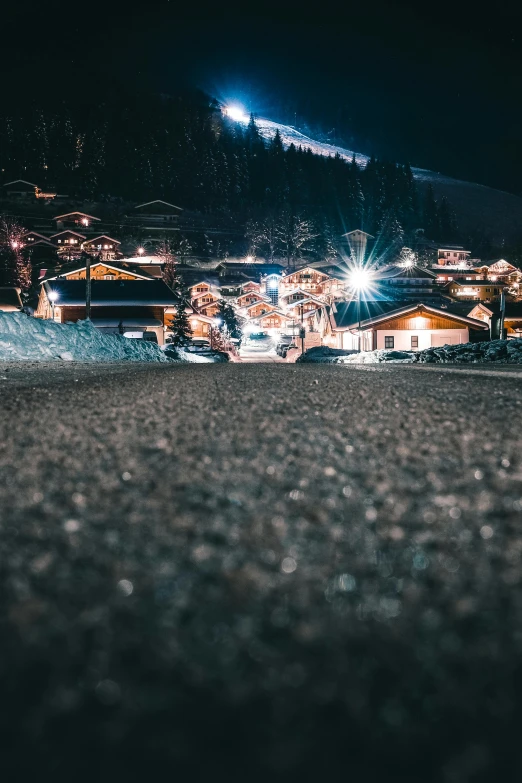 a person riding a snowboard down a snow covered slope, a tilt shift photo, by Sebastian Spreng, pexels contest winner, happening, nightime village background, paved roads, festival. scenic view at night, in the dolomites