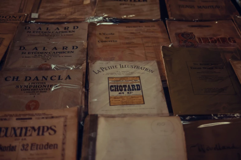 a pile of books sitting on top of a table, an album cover, by Raphaël Collin, unsplash, visual art, early 1900s newspaper, mustard, displayed in a museum, apothecary