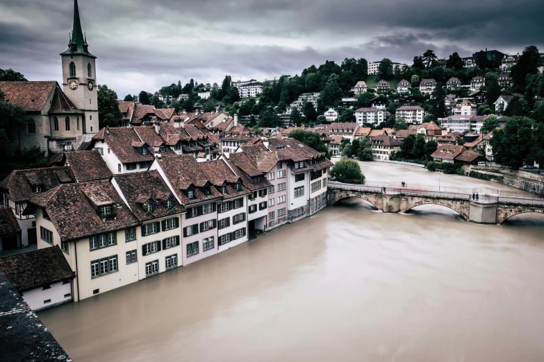 a river running through a town next to a bridge, inspired by Karl Stauffer-Bern, pexels contest winner, renaissance, ominous photo, brown water, white buildings, 4k image”
