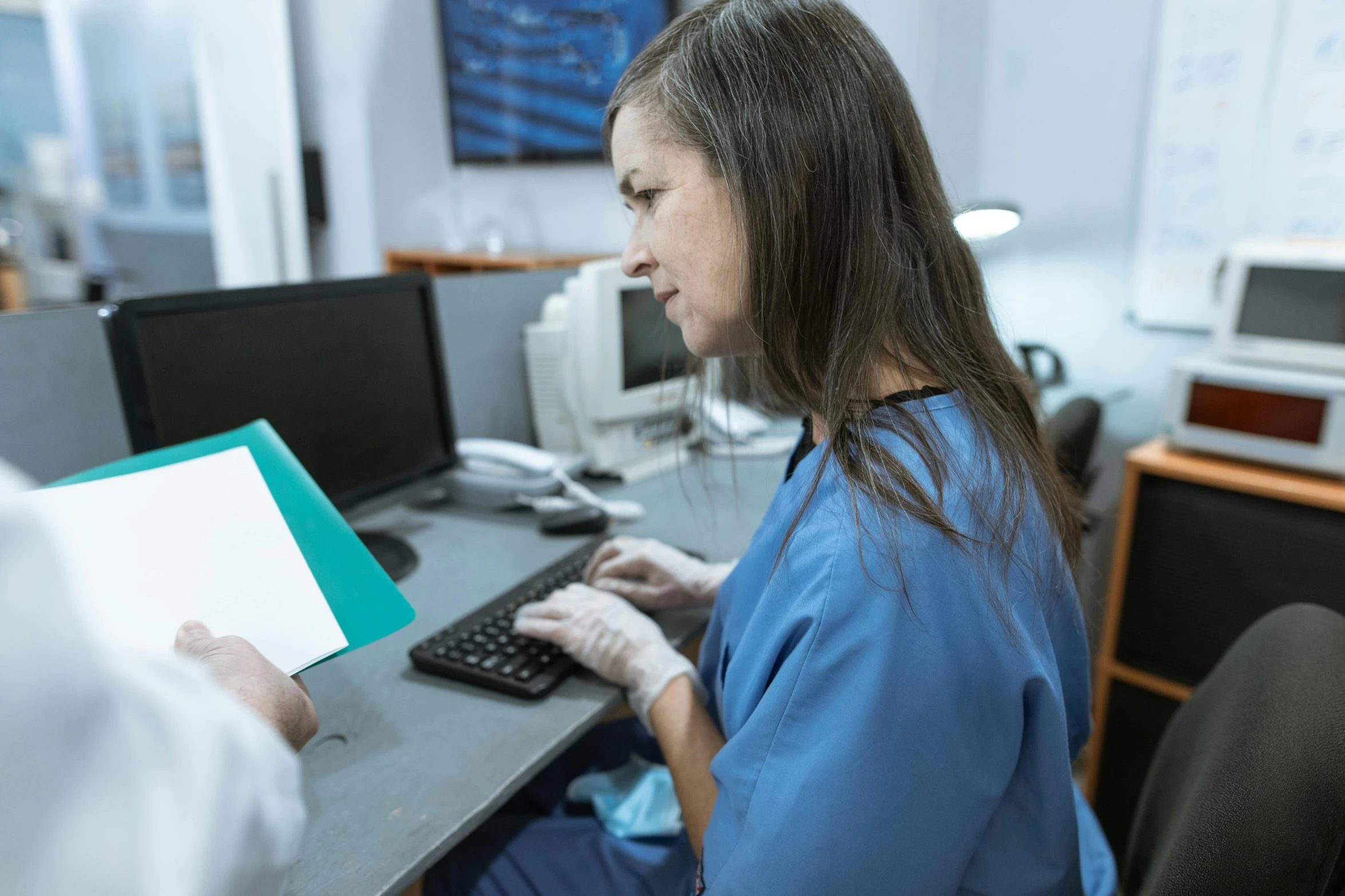 a woman sitting at a desk using a computer, nurse scrubs, lachlan bailey, profile image, still photograph