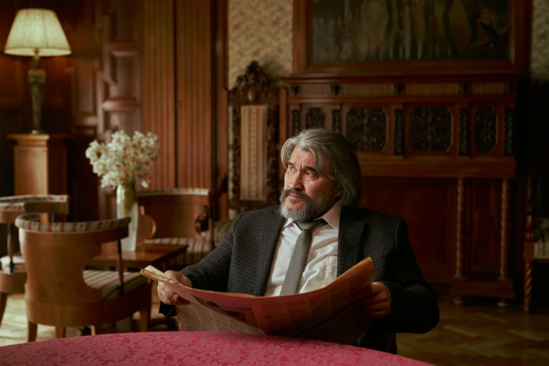 a man sitting at a table reading a newspaper, inspired by Karl Gerstner, pexels contest winner, art nouveau, in their noble mansion, slavoj zizek, production still, sebastien chabal