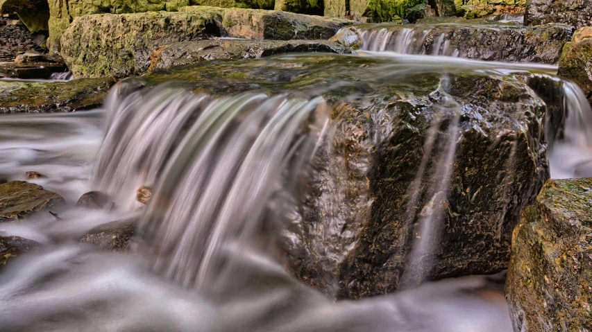 a small waterfall flowing through a lush green forest, an album cover, pexels contest winner, water feature, panoramic shot, waterwheels, rock pools