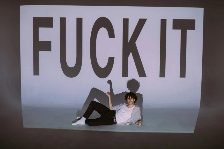 a woman sitting on the ground in front of a sign, inspired by Fei Danxu, fluxus, finn wolfhard, doing a sassy pose, concert photo, psycho stupid fuck it insane