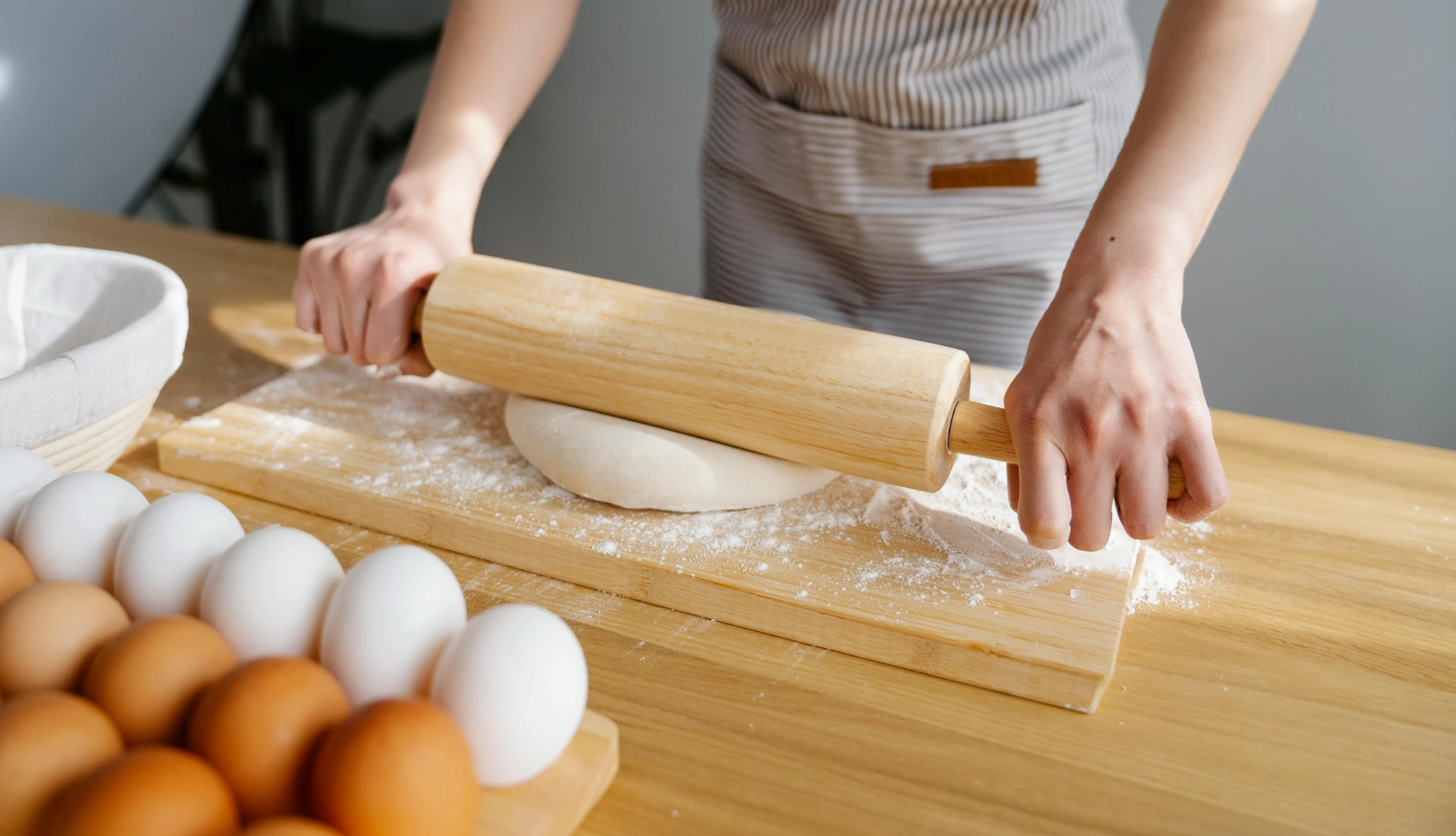 a person rolling out dough on a wooden table, trending on pexels, holding a wooden staff, straight neck, product introduction photo