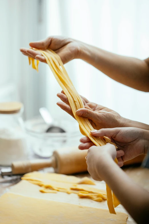 a couple of people that are making some food, trending on pexels, process art, intricate pasta waves, closeup of arms, soft natural light, ribbon