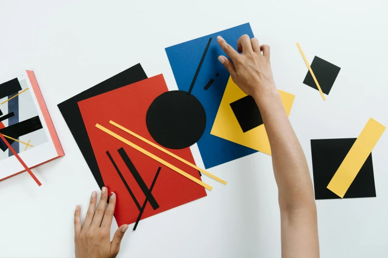 a person cutting out a piece of paper with scissors, an album cover, pexels contest winner, suprematism, 3 colour print, fan favorite, ( ( bauhaus ) ), coloured