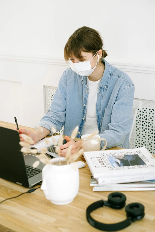 a woman sitting at a table in front of a laptop, dust mask, styling, gemma chen, clean environment