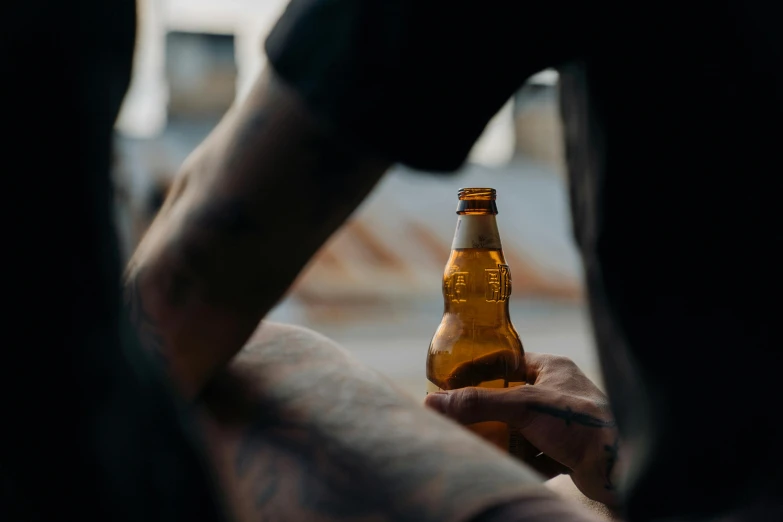 a close up of a person holding a beer bottle, pexels contest winner, man sitting facing away, lean man with light tan skin, profile image, no watermarks