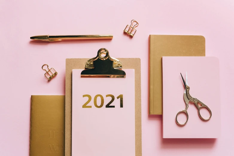 a notepad sitting on top of a clipboard next to a pair of scissors, trending on pexels, aestheticism, pink and gold, new years eve, thumbnail, from star trek 2021