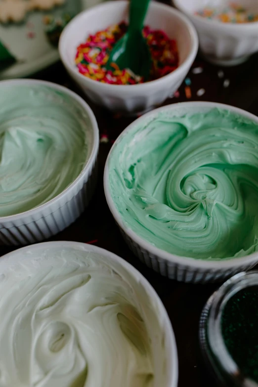 a table topped with bowls of frosting and sprinkles, trending on pexels, process art, green colored skin, embossed paint, green and white, medium detail