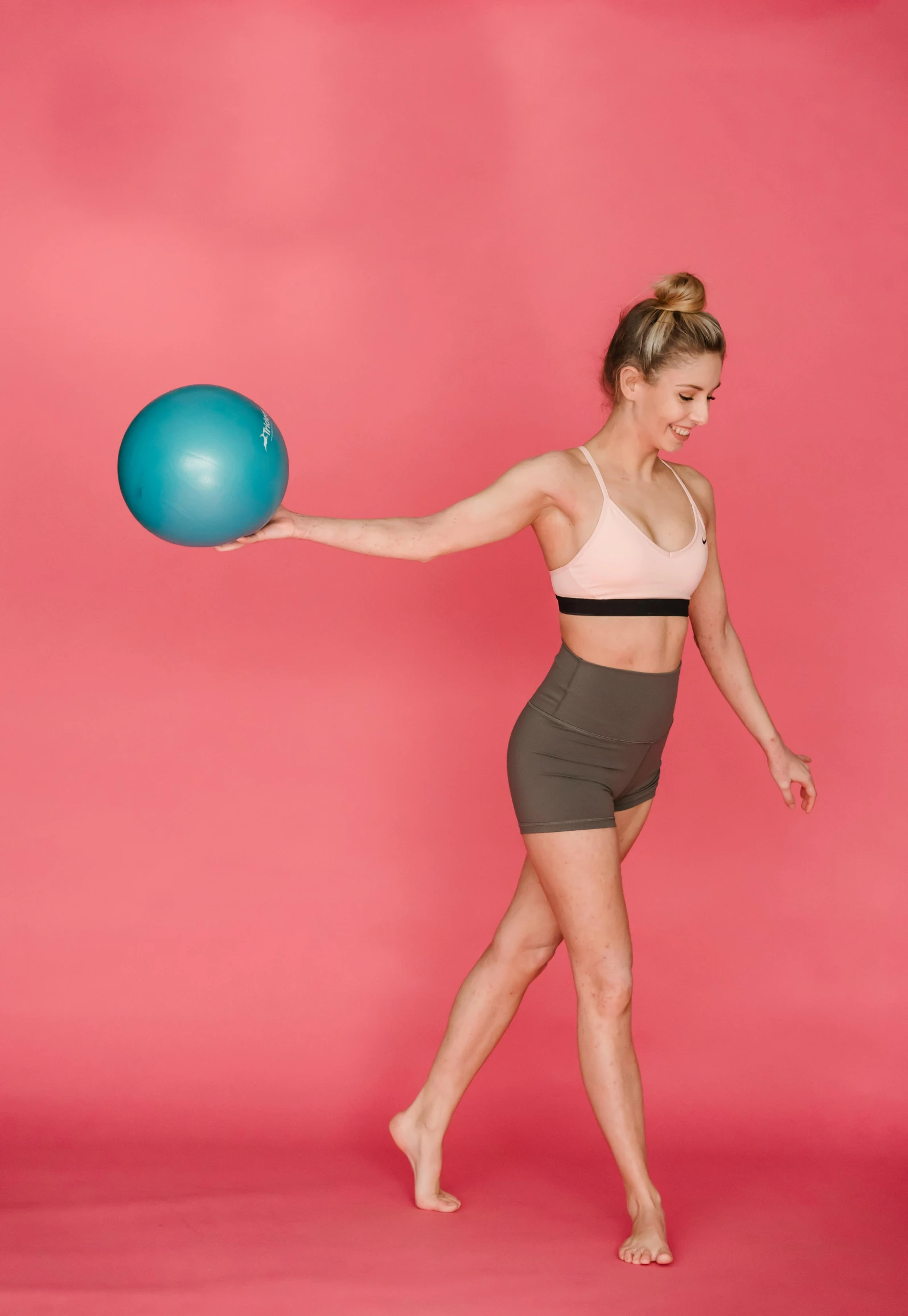 a woman holding a blue ball on a pink background, a colorized photo, bent - over posture, widest hips, sydney sweeney, 2 arms and 2 legs